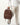 person carrying leather backpack by top handle
