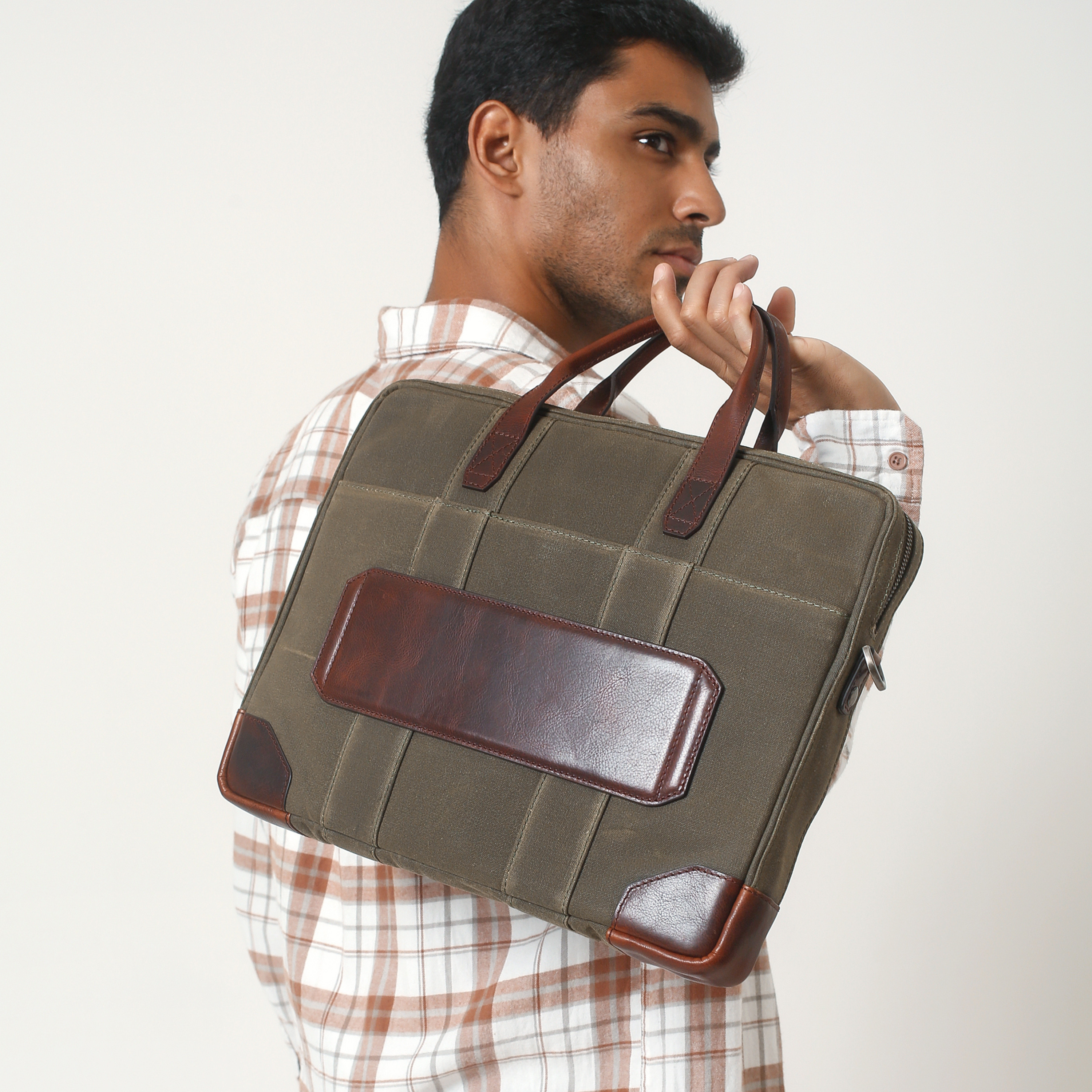 person showing backside trolley strap on waxed canvas and pull up leather laptop briefcase